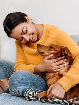 a woman with her small brown puppy sitting on a gray couch